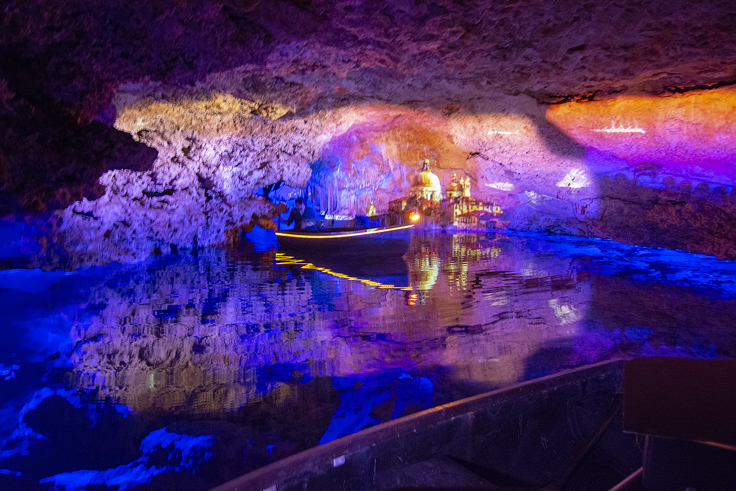 Cave Interior Lit In Colors And Boat On The Lake